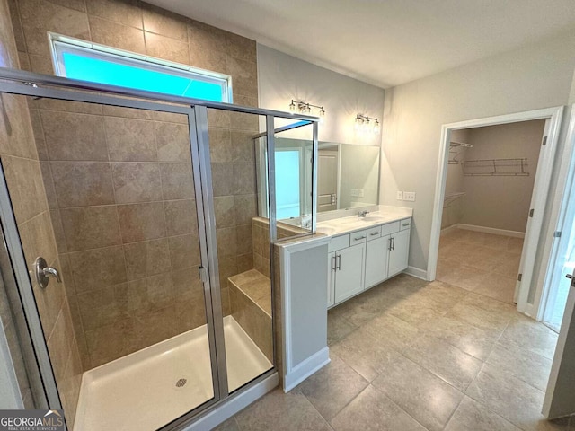 full bath with a stall shower, a spacious closet, baseboards, and vanity