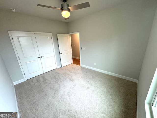 unfurnished bedroom with ceiling fan, a closet, carpet, and baseboards