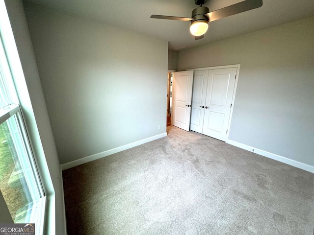 unfurnished bedroom with a ceiling fan, a closet, baseboards, and carpet flooring