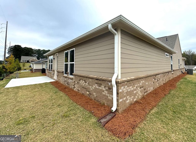 view of home's exterior featuring brick siding, a yard, and a patio