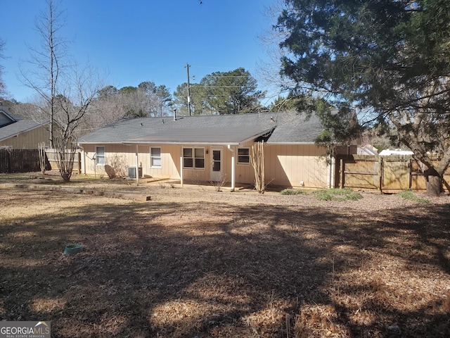 rear view of property with central AC unit, fence, and a gate