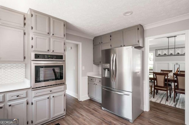 kitchen with dark wood finished floors, crown molding, appliances with stainless steel finishes, and gray cabinetry