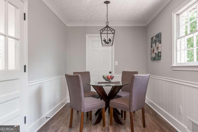 dining room with visible vents, dark wood-type flooring, an inviting chandelier, and a wainscoted wall