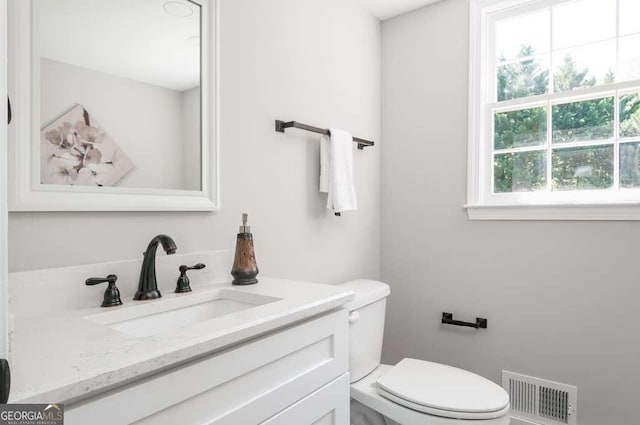 bathroom with vanity, toilet, and visible vents