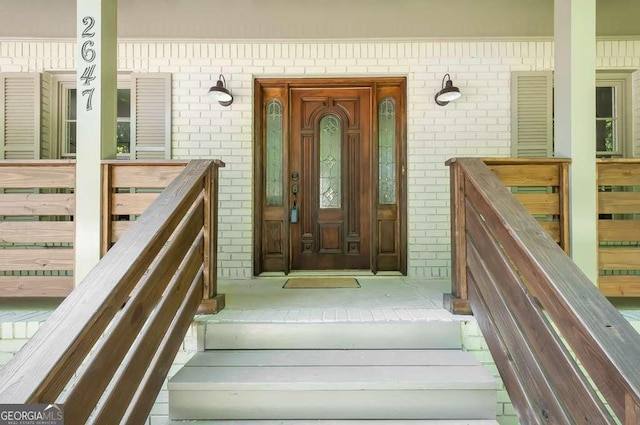 doorway to property featuring brick siding and covered porch