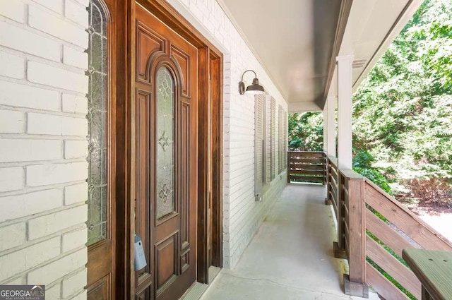 doorway to property featuring brick siding and a porch