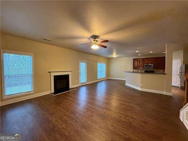 unfurnished living room with dark wood-type flooring, visible vents, a fireplace, and baseboards