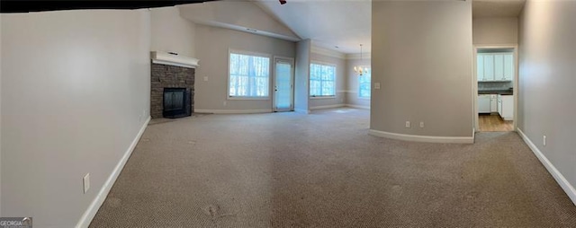 unfurnished living room with carpet, a stone fireplace, and baseboards