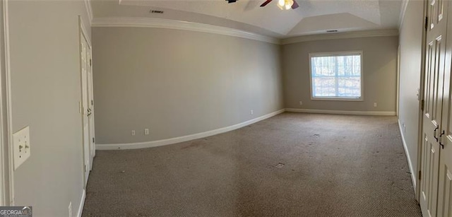 spare room with a tray ceiling, ornamental molding, carpet floors, and baseboards