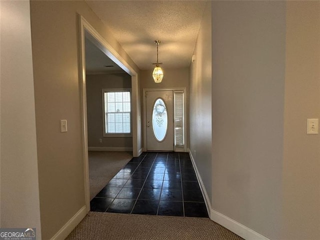 entryway featuring dark tile patterned floors, baseboards, dark carpet, and a textured ceiling