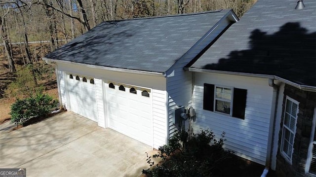 view of property exterior with a detached garage and roof with shingles