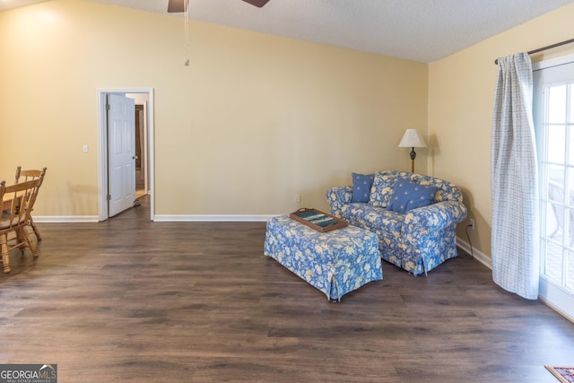 living area featuring a ceiling fan, vaulted ceiling, baseboards, and wood finished floors