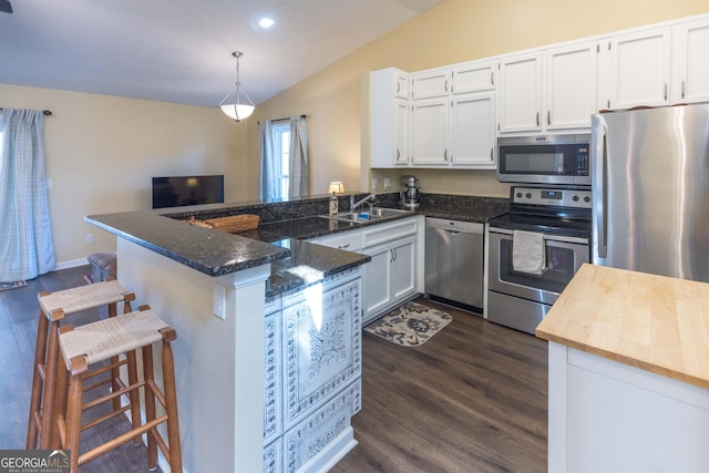 kitchen featuring dark wood finished floors, stainless steel appliances, white cabinets, a sink, and a peninsula