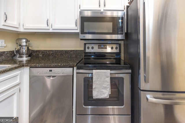 kitchen featuring stainless steel appliances, dark stone counters, and white cabinets