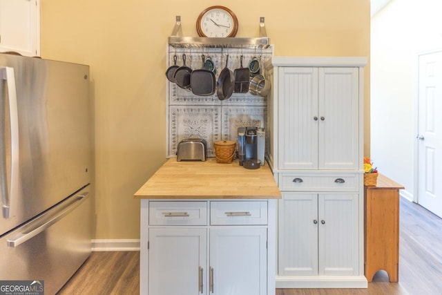 kitchen with baseboards, wooden counters, wood finished floors, and freestanding refrigerator