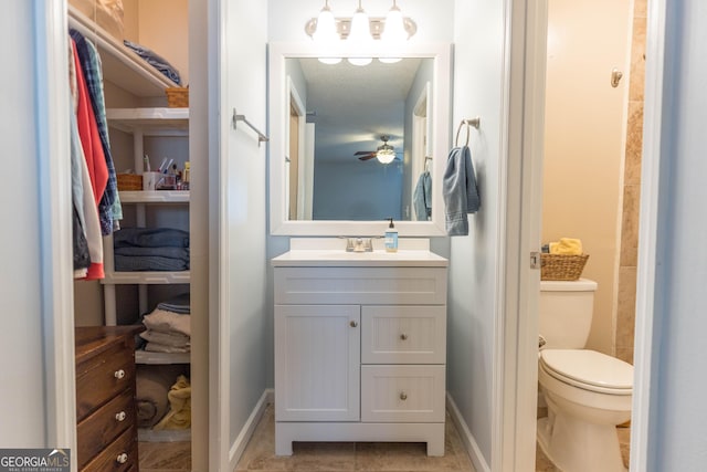 bathroom with toilet, tile patterned floors, baseboards, and vanity