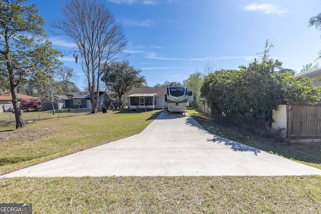 view of front of property featuring driveway, a front yard, and fence