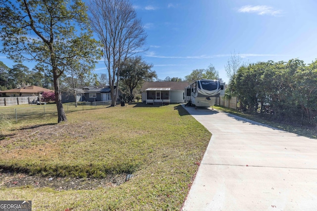 view of front of home with concrete driveway, fence, and a front lawn