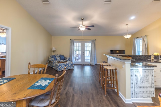 kitchen featuring dark wood-style flooring, visible vents, a kitchen breakfast bar, vaulted ceiling, and french doors