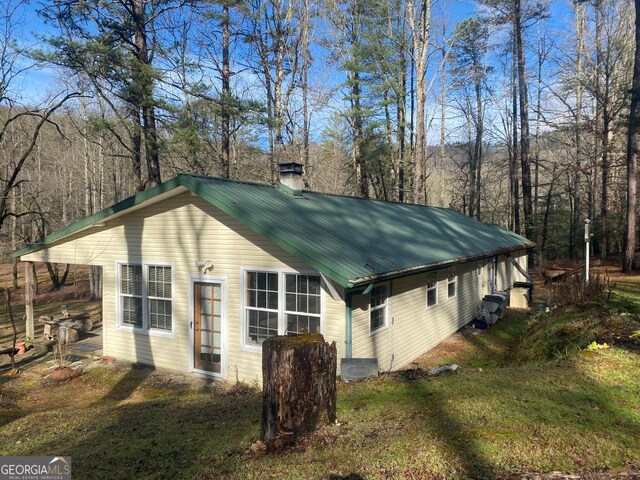 view of home's exterior featuring metal roof and a chimney