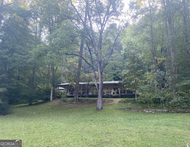 view of front of property featuring a front yard and a wooded view