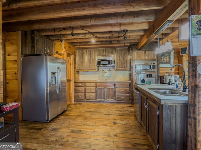 kitchen with stainless steel appliances, a sink, beam ceiling, hardwood / wood-style floors, and pendant lighting