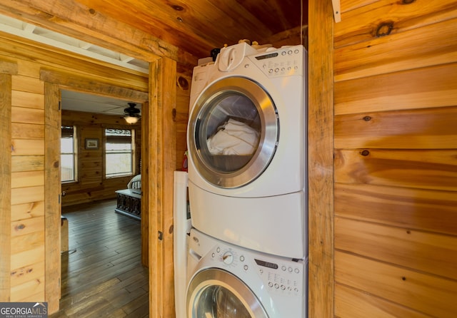 laundry area featuring wood walls, laundry area, wood-type flooring, stacked washing maching and dryer, and wood ceiling
