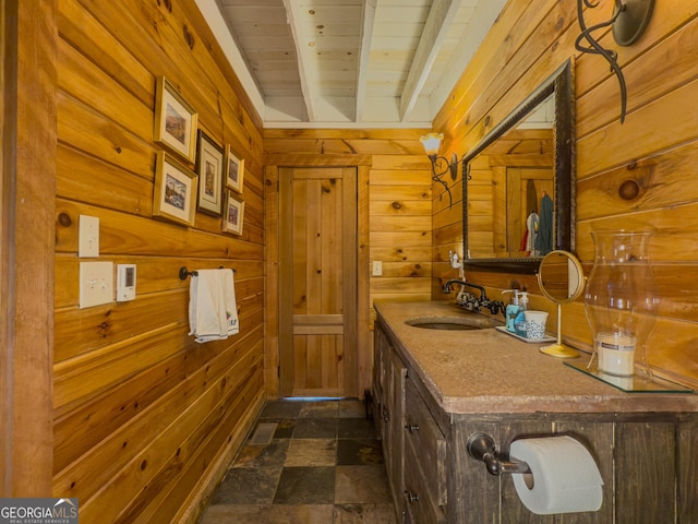 bathroom with stone finish flooring, wooden walls, vanity, wooden ceiling, and beamed ceiling