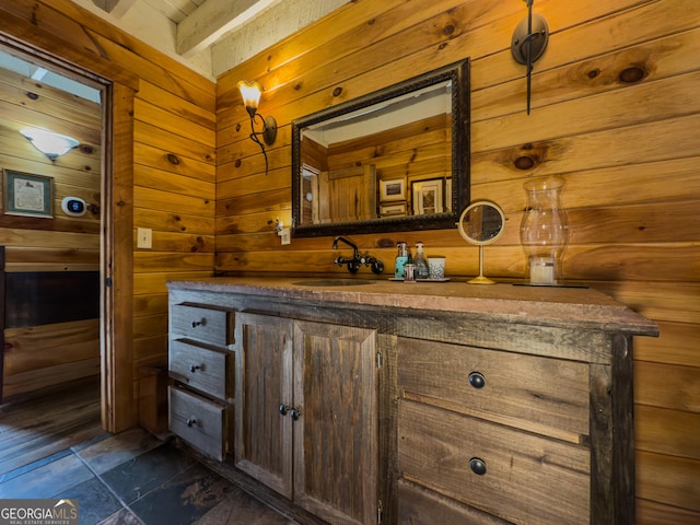 bathroom featuring vanity, wooden walls, and stone finish floor