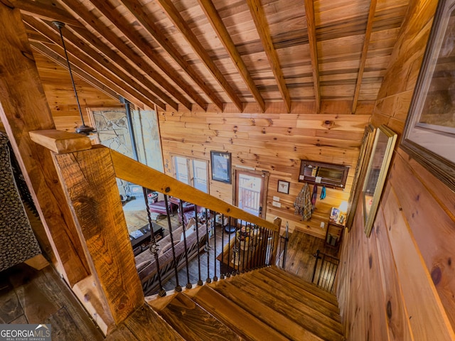 staircase featuring beam ceiling, hardwood / wood-style flooring, and wooden walls