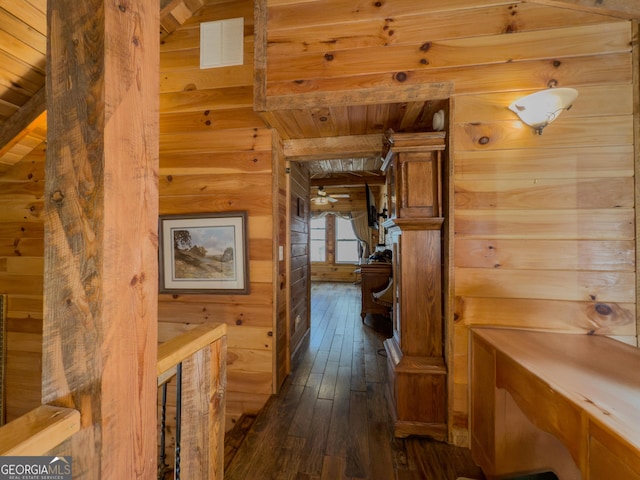 corridor with wood walls, dark wood-style flooring, wooden ceiling, and visible vents