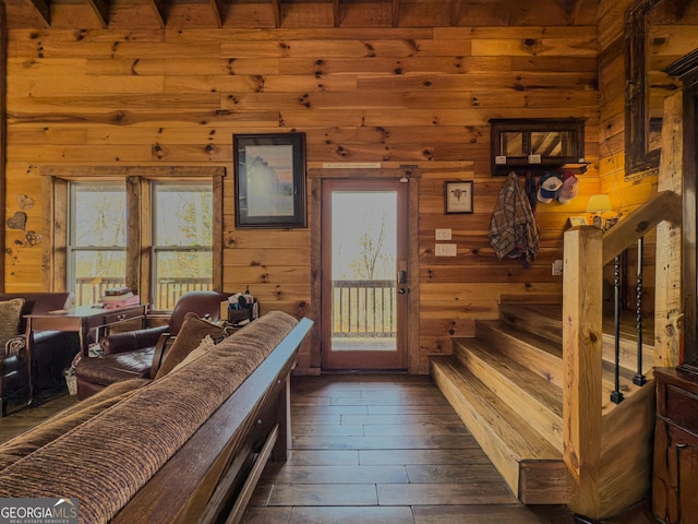 living room with stairs, dark wood-type flooring, and wood walls