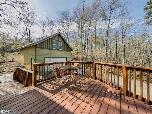 wooden terrace featuring a detached garage and outdoor dining area