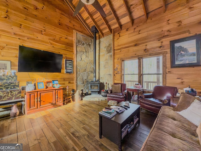 living area with wood ceiling, a wood stove, wooden walls, and beam ceiling