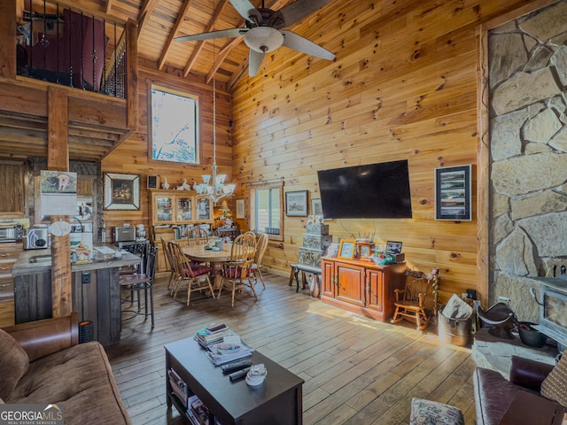 living area with hardwood / wood-style flooring, ceiling fan with notable chandelier, high vaulted ceiling, wooden walls, and wood ceiling