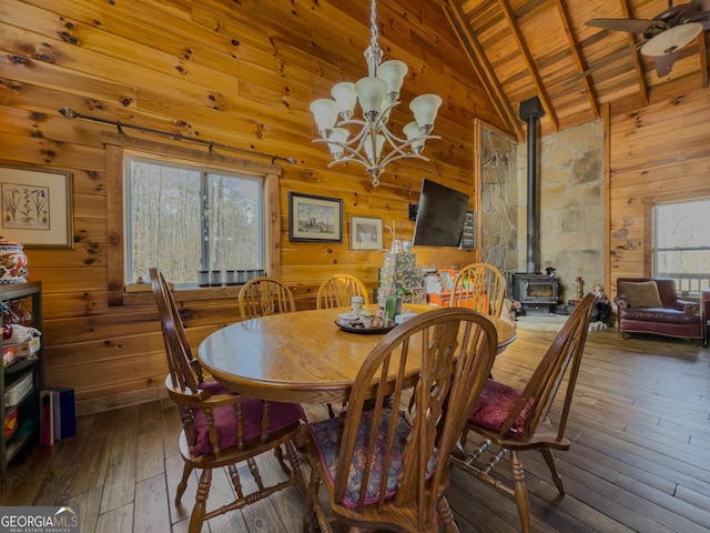 dining area featuring hardwood / wood-style flooring, a wood stove, wooden walls, and a healthy amount of sunlight