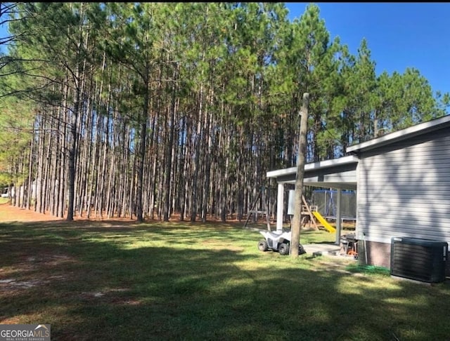 view of yard with a carport, cooling unit, and a playground