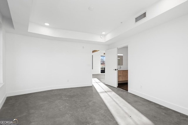 unfurnished room with baseboards, visible vents, a tray ceiling, and recessed lighting