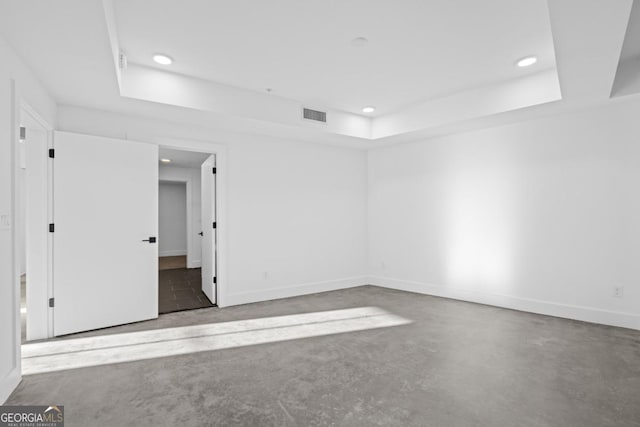 spare room with visible vents, concrete floors, a tray ceiling, and recessed lighting