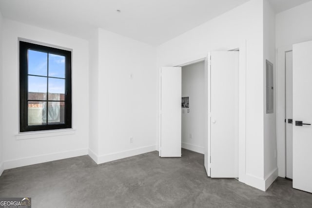 unfurnished bedroom featuring electric panel, concrete floors, and baseboards