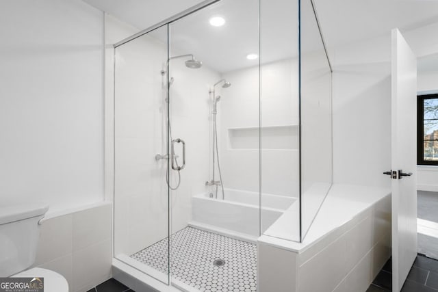 bathroom featuring tile patterned flooring, a shower stall, and toilet