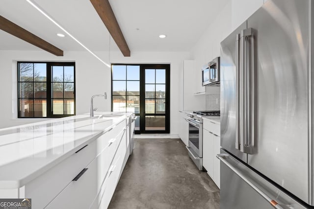 kitchen with beam ceiling, stainless steel appliances, white cabinetry, modern cabinets, and concrete flooring