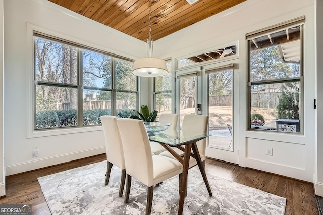 dining room featuring wooden ceiling, plenty of natural light, baseboards, and wood finished floors