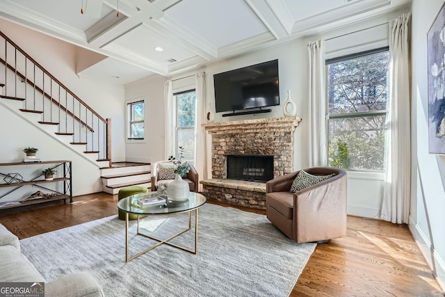 living area with stairway, coffered ceiling, wood finished floors, and beam ceiling