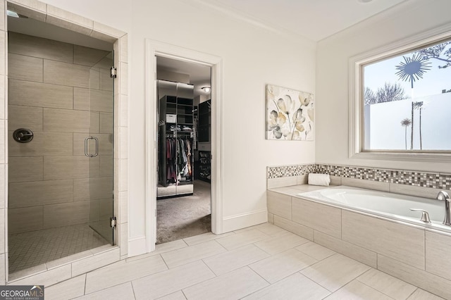 bathroom with a spacious closet, a stall shower, tile patterned flooring, baseboards, and a bath