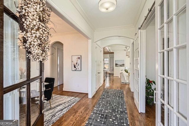 hallway with ornamental molding, arched walkways, french doors, and wood finished floors