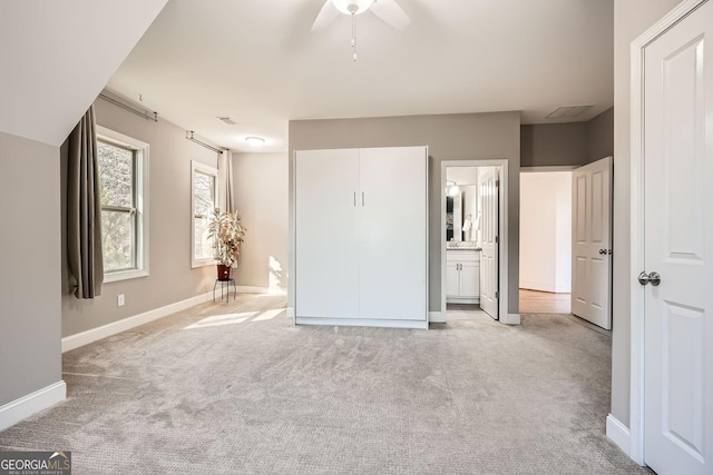 unfurnished bedroom with baseboards, ensuite bathroom, visible vents, and light colored carpet