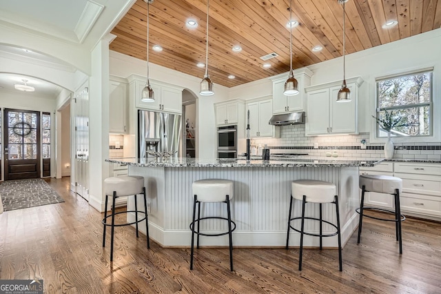 kitchen featuring appliances with stainless steel finishes, arched walkways, wood ceiling, and under cabinet range hood