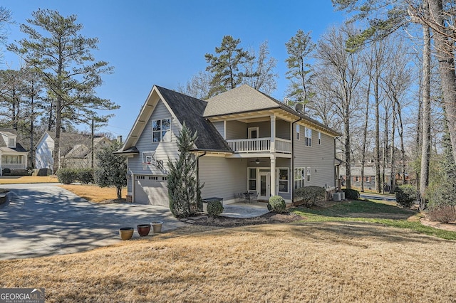 back of house with a lawn, central AC unit, a balcony, a garage, and driveway