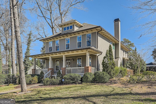 american foursquare style home with a front lawn, a chimney, and a porch